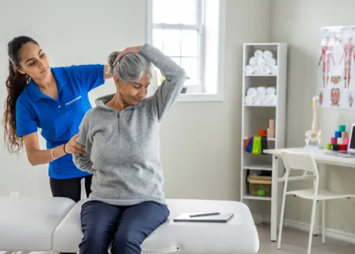 an old woman with physiotherapist having back pain physiotherapy at home